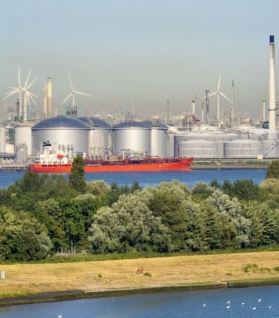 Past and future, wind turbines and oil storage tanks in the Maas Estuary, approaching Rotterdam Container Port, the Netherlands