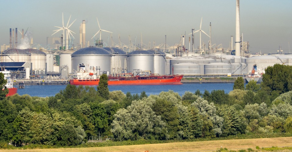 Past and future, wind turbines and oil storage tanks in the Maas Estuary, approaching Rotterdam Container Port, the Netherlands