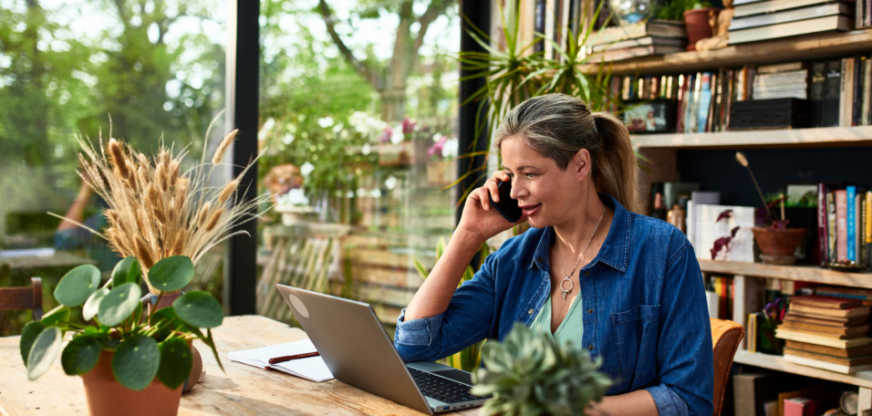Businesswoman using mobile phone in front of laptop