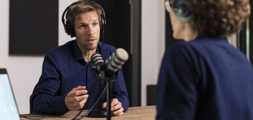 Man wearing headset talking with guest in recording studio