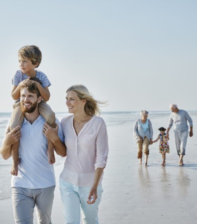 Happy extended family strolling on the beach